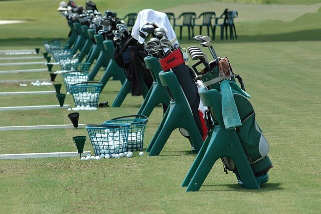 Mehrere Golftaschen auf einer Driving Range. Viele Golfplätze im Tessin haben eine Driving Range.